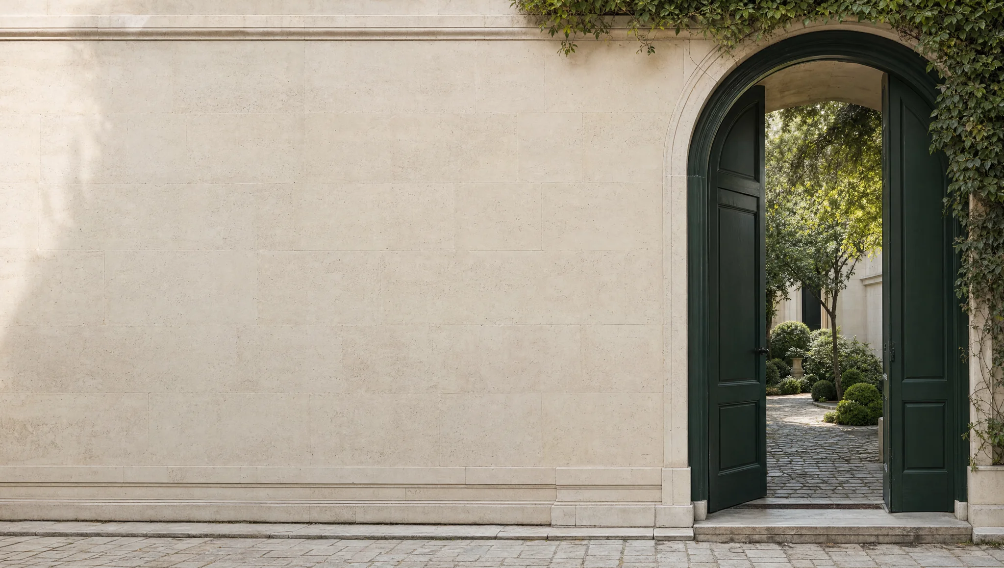An open evergreen doorway in pale stone, leading to a quiet garden
