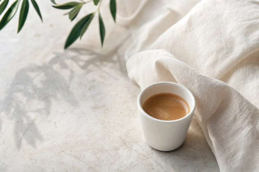 A ceramic coffee cup and linen on pale stone